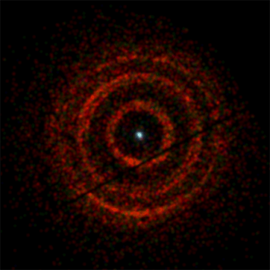 Rings of X-ray light centered on V404 Cygni, a binary system containing an erupting black hole (dot at center), were imaged by the X-ray Telescope aboard NASA's Swift satellite from June 30 to July 4. A narrow gap splits the middle ring in two. Color indicates the energy of the X-rays, with red representing the lowest (800 to 1,500 electron volts, eV), green for medium (1,500 to 2,500 eV), and the most energetic (2,500 to 5,000 eV) shown in blue. For comparison, visible light has energies ranging from about 2 to 3 eV. The dark lines running diagonally through the image are artifacts of the imaging system.